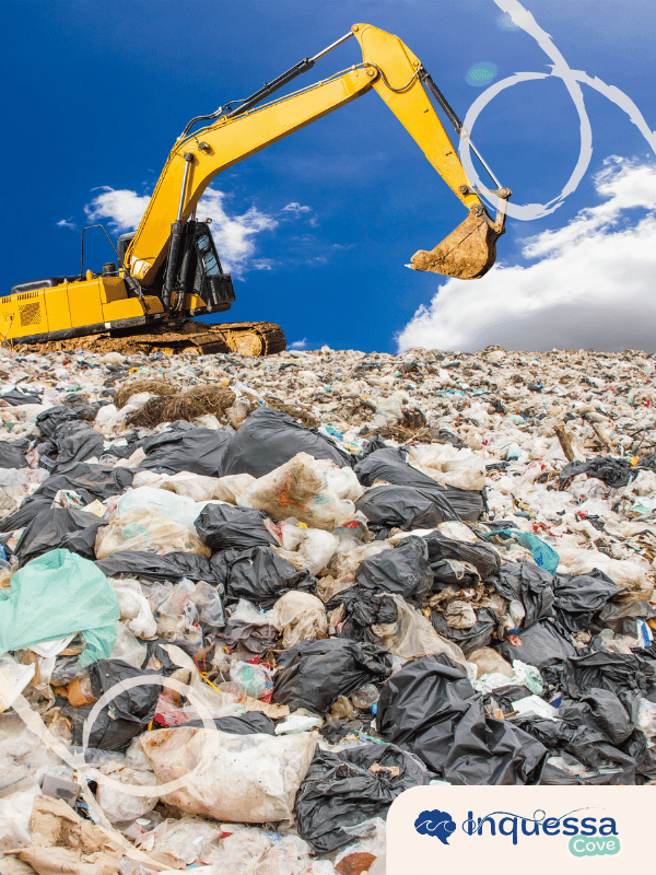 Excavator working on a large landfill covered with plastic bags and other waste