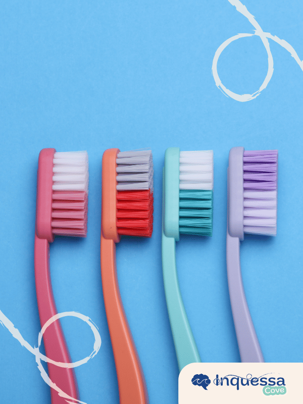 Four colorful plastic toothbrushes arranged side by side on a blue background