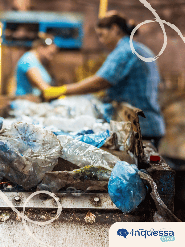 Plastic waste moving along a sorting conveyor with workers in the background