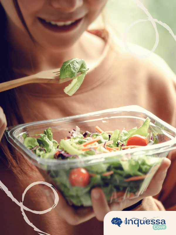 Person eating salad from a clear plastic food container