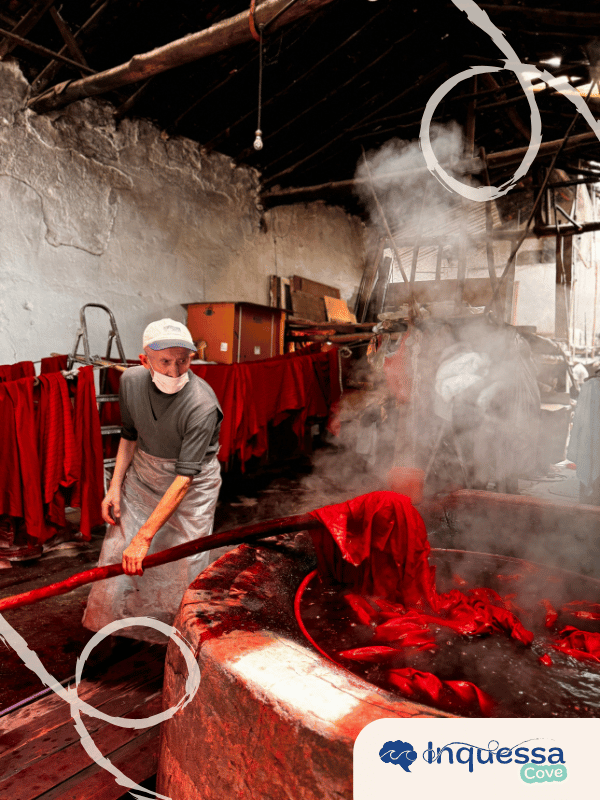 Worker handling red fabric in a steaming industrial process